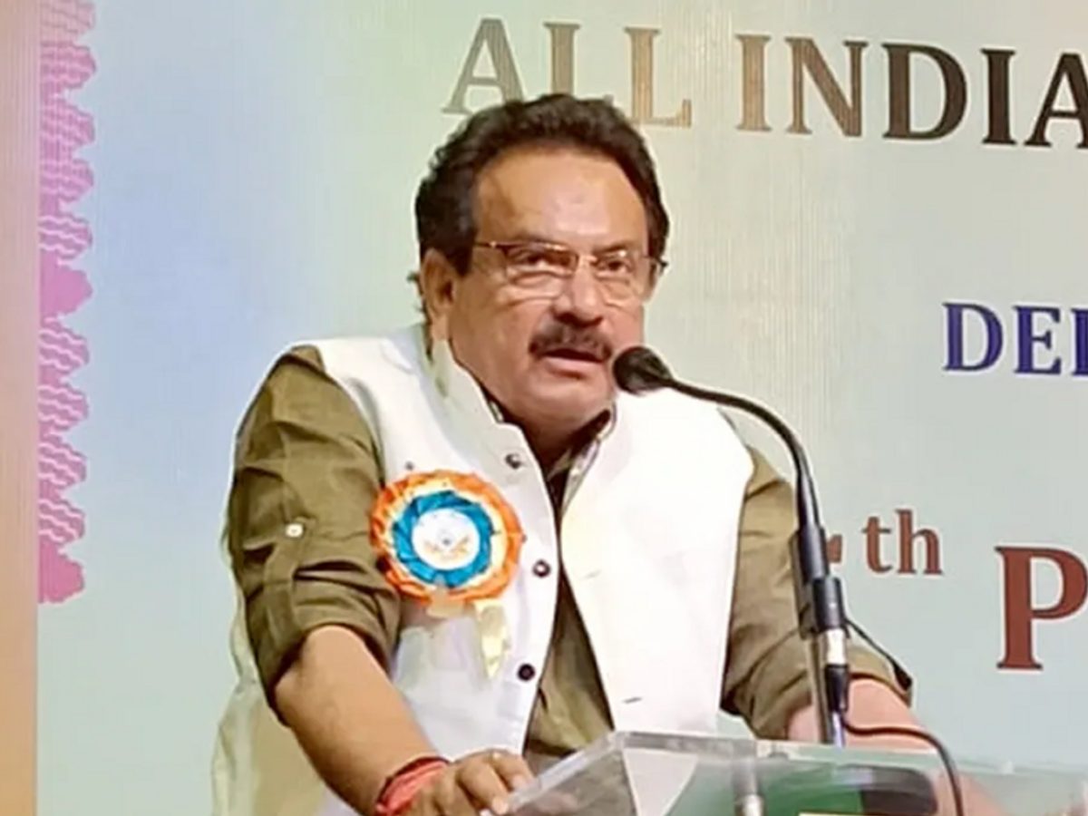 Satyapal Singh Baghel speaking at a glass lectern in front of an event banner