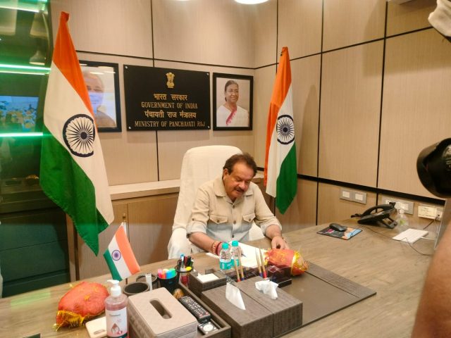 Satyapal Singh Baghel seated at a desk beneath a sign reading Government of India, Ministry of Panchayati Raj
